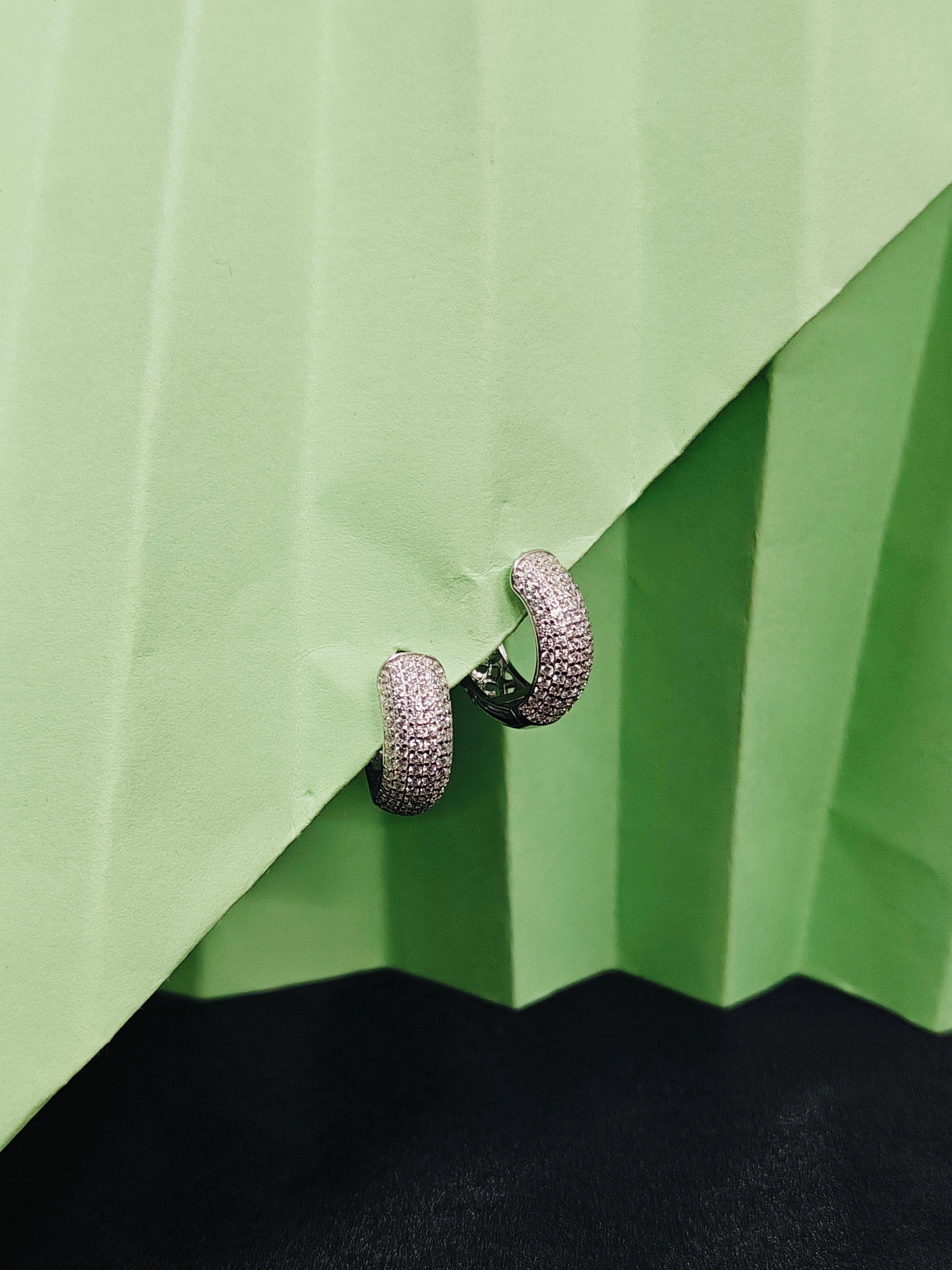 Silver hoop earrings on a green fabric background